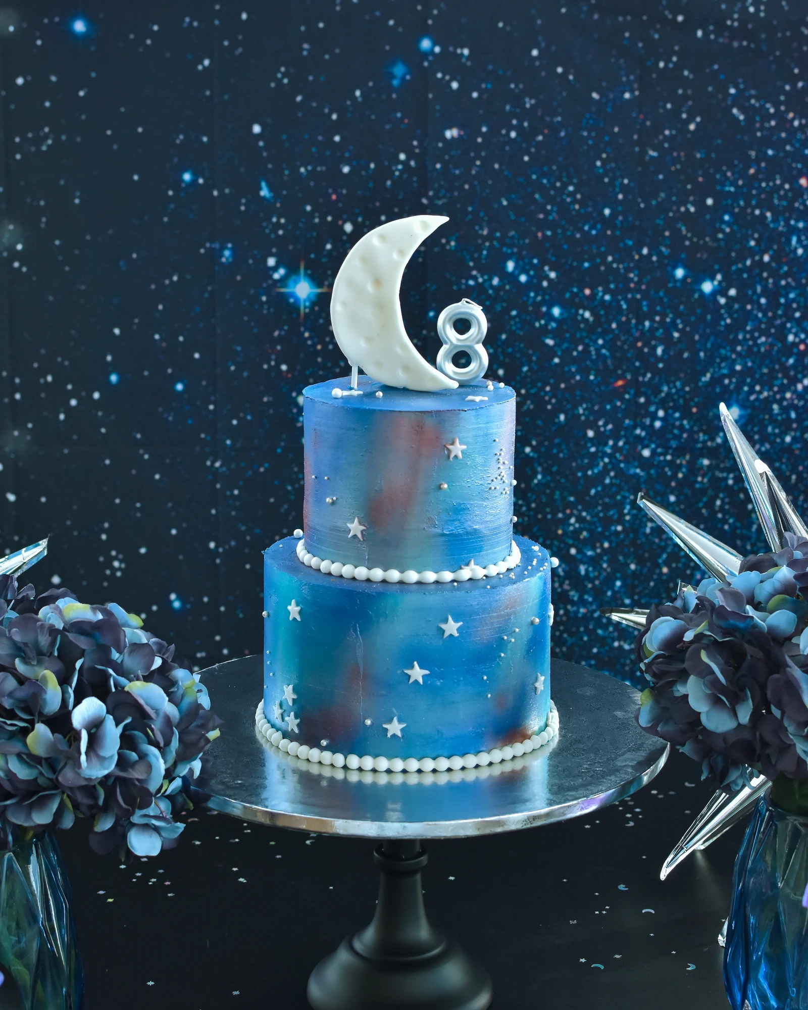 Bolo de aniversário azul com dois andares e tema espacial.