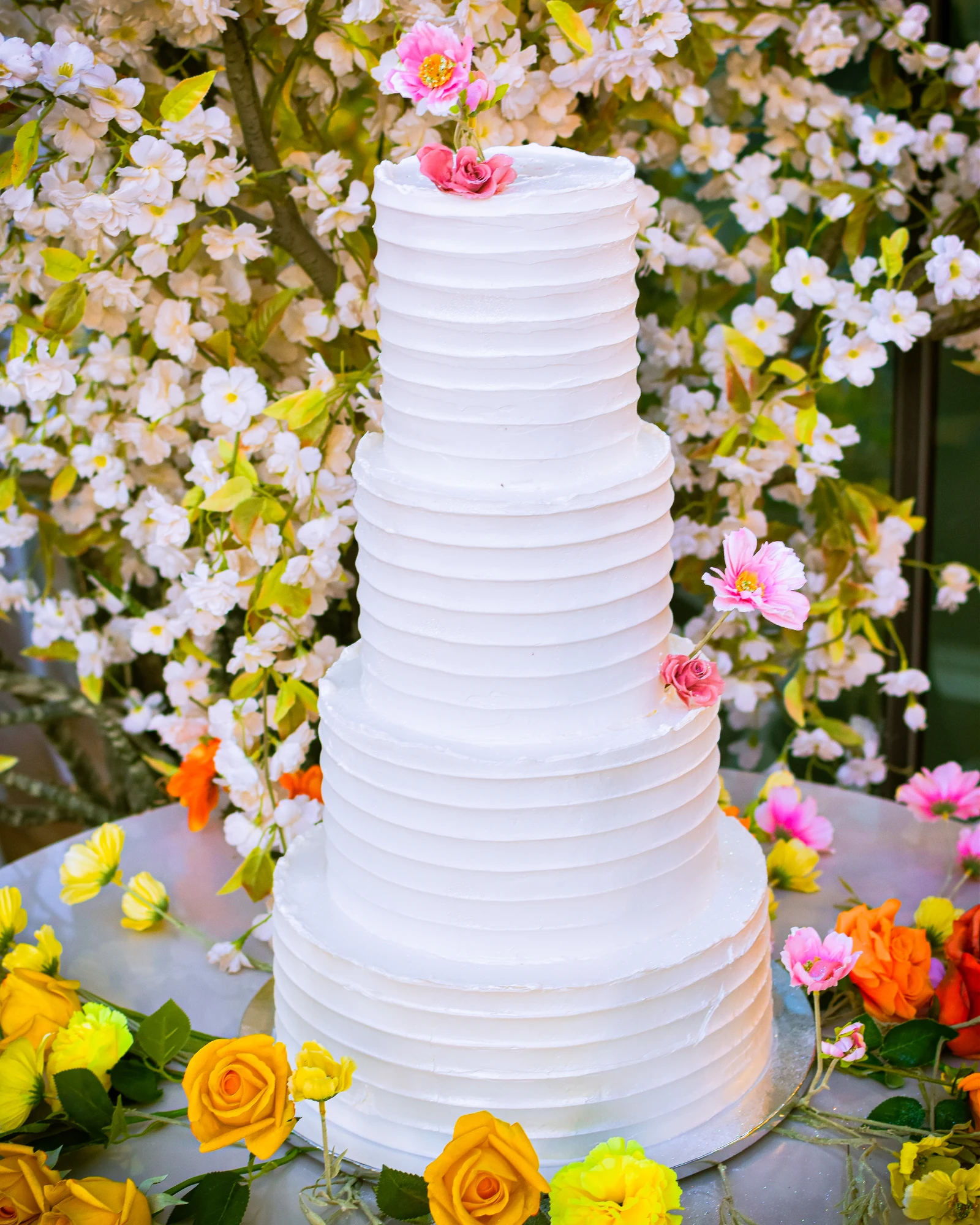Bolo de casamento branco com três andares e flores.
