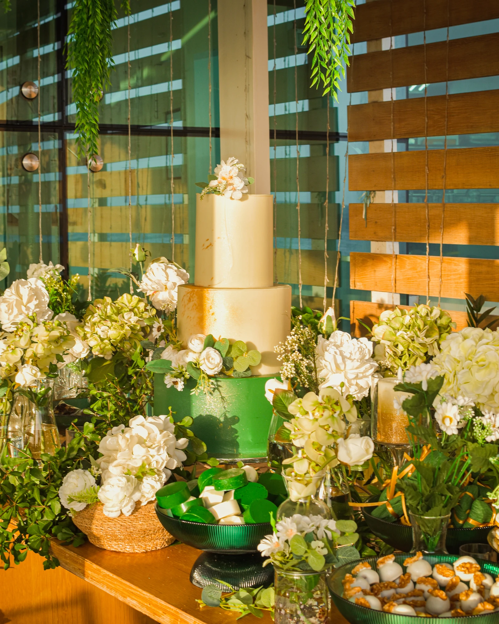 Mesa de festa com bolo verde e dourado.