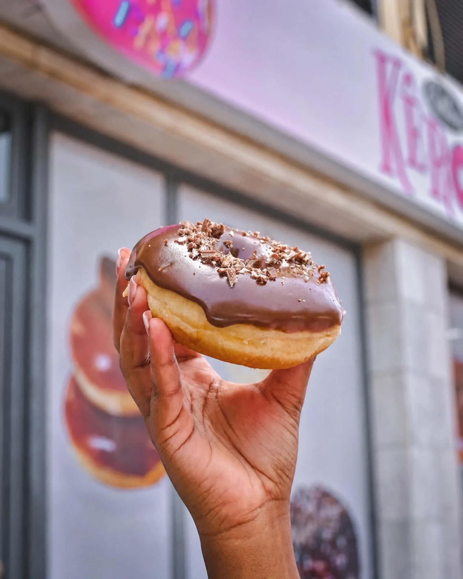 Donut coberto de chocolate em frente à montra da Kêro Donuts, no Plateau.