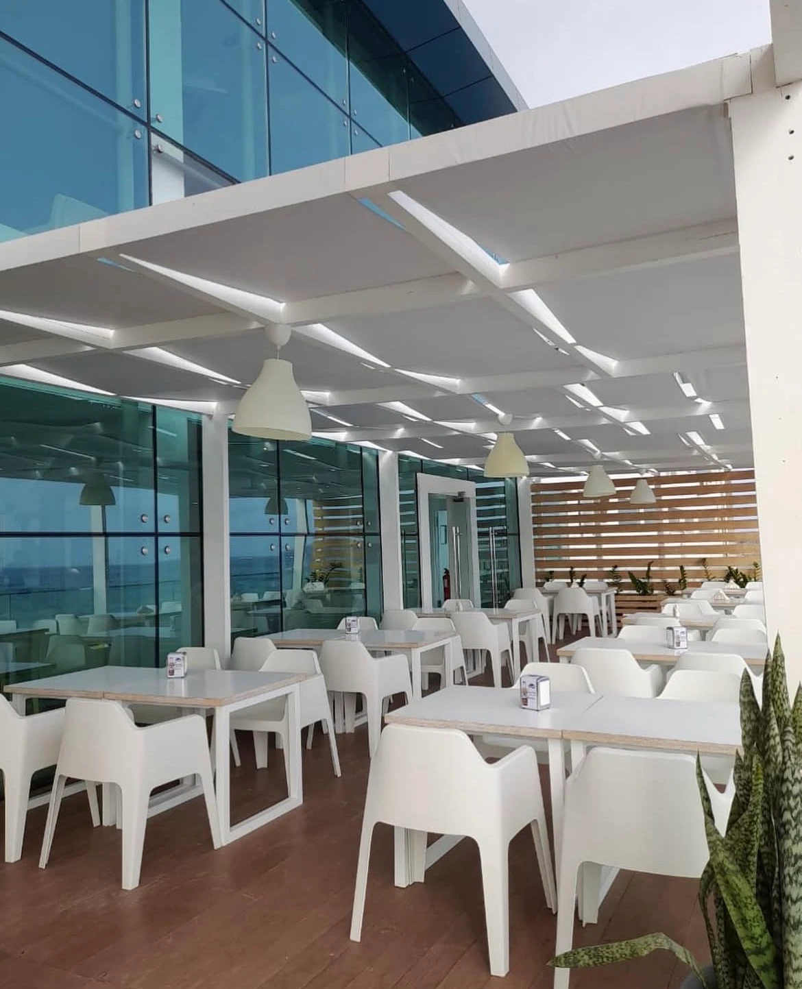 Esplanada da Kêro Praia Shopping, com mesas e cadeiras brancas junto à fachada envidraçada.